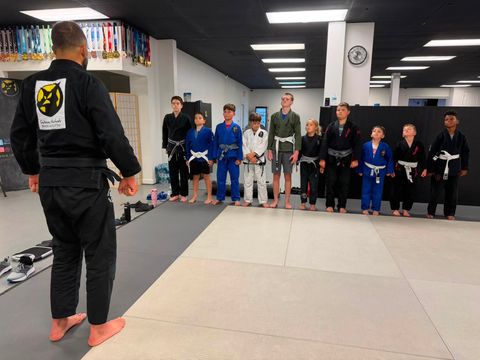 Kids & Teen BJJ students in gis lined up for class with their instructor