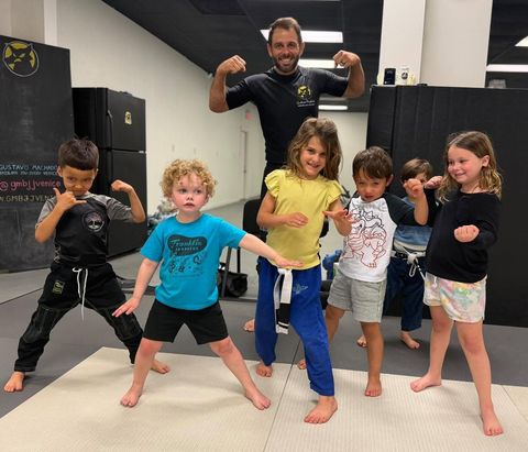 Little Champs Kids BJJ students striking a pose with their coach at Gustavo Machado BJJ Venice